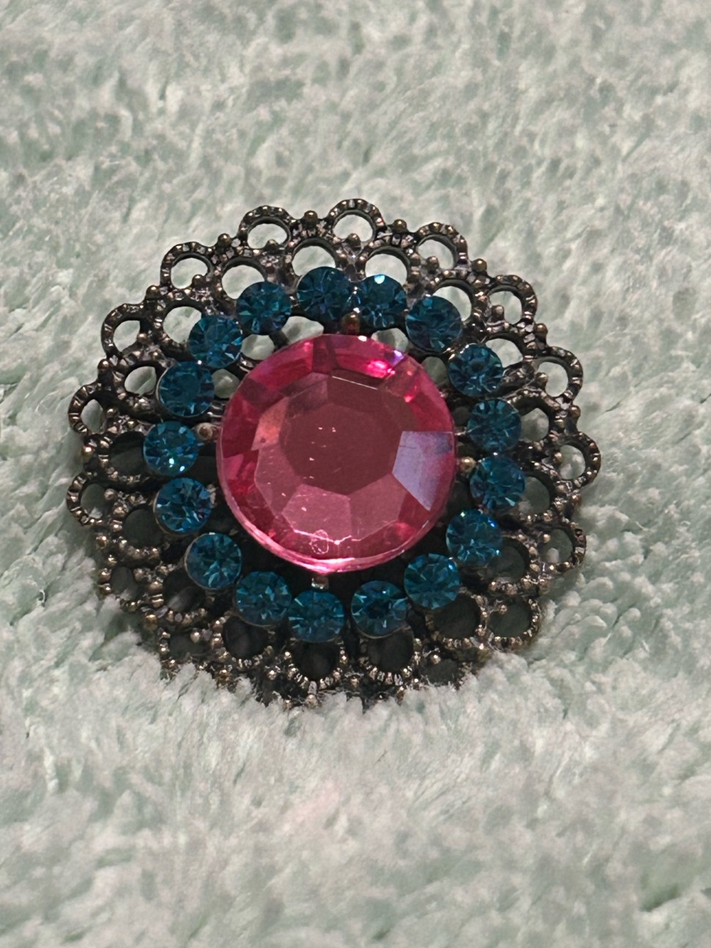 Vintage metal filigree brooch featuring a large pink faceted crystal